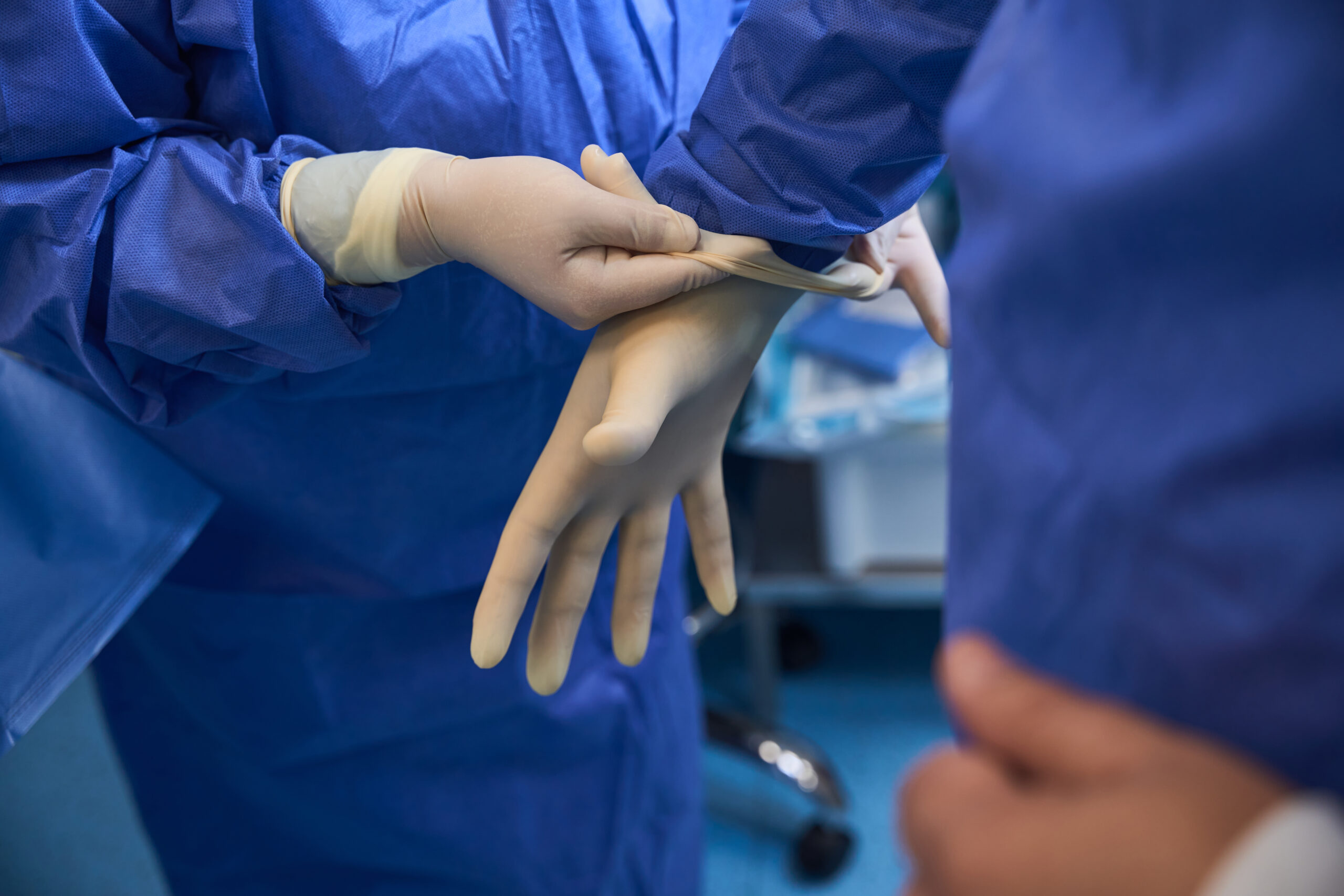 Close-up of surgeon wearing sterile gloves in OR